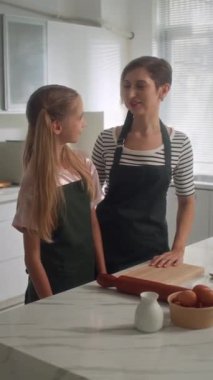 Ev mutfağında yemek pişiren beyaz anne ve kızın dikey portresi.
