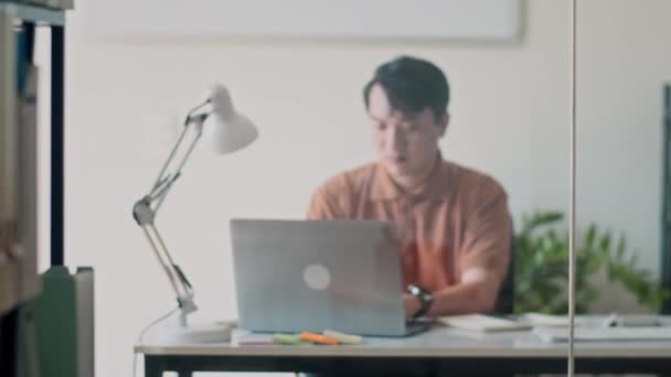 ワイヤレスラップトップで作業し 現代のオフィスでノートを作る深刻なアジアのビジネスマンのパンショット — ストック動画