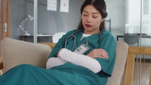 Yorgun Asyalı Hemşirenin Uzun Bir Gününden Sonra Klinikteki Kanepede Uyuması — Stok video