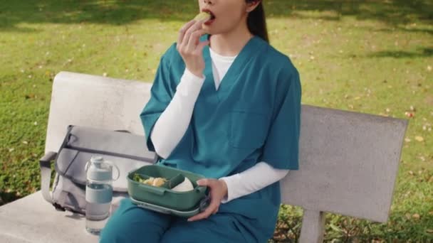 Strzał Dziesiątkę Młodego Azjatyckiego Pracownika Służby Zdrowia Jedzącego Pudełka Śniadaniowego — Wideo stockowe