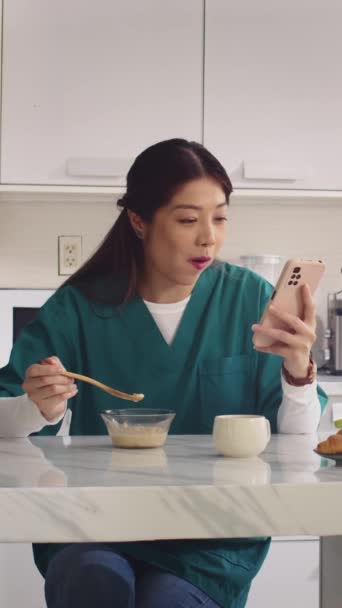 Vertical Tiro Enfermeira Asiática Uniforme Médico Comer Iogurte Usando Telefone — Vídeo de Stock