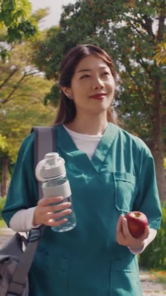Tiro Vertical Joven Enfermera Asiática Sosteniendo Botella Agua Manzana Cuando — Vídeo de stock
