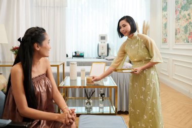 Ağda yapan kuaför müşteriye kahve getiriyor.