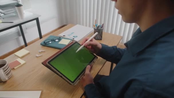 オフィスの机で働いている間緑色のクロマのキー スクリーンが付いているタブレットの男性のグラフィックデザイナーのデッサンのクロップされたショット — ストック動画