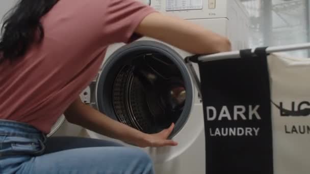ダークランドリーで洗濯機をローディングする女性のクロップショット — ストック動画