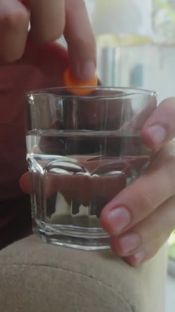 一个无法辨认的人把冒出的泡沫石碑放在装有水的玻璃杯中的垂直镜头 — 图库视频影像