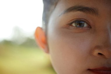 Genç bayan Asyalı tekvando atletinin yarı yüzü açık havada duran gri gözlü.