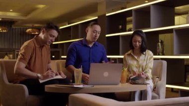 Üç farklı girişimcinin orta uzunlukta bir kısmı otel odasında proje başlatmayı tartışıyor.
