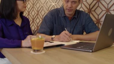 Beyaz erkek avukatın dinlenme odasında dizüstü bilgisayarla masada oturan kadın müşteriye yeni anlaşmayı açıklarken görüntüsü.