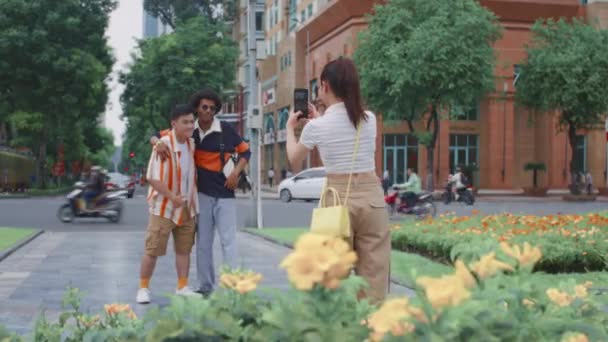 都市を歩いている間に携帯電話で彼女の男性の友人を撮影した女性の長いショット — ストック動画
