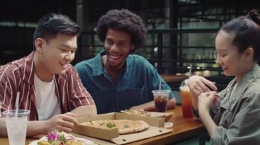 Hafta sonunu şehirde birlikte geçirirken yemek katında pizza yiyen orta boy arkadaşlar.