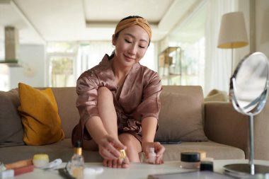 Gülümseyen kadın evde pedikür yaptıktan sonra oje sürüyor.
