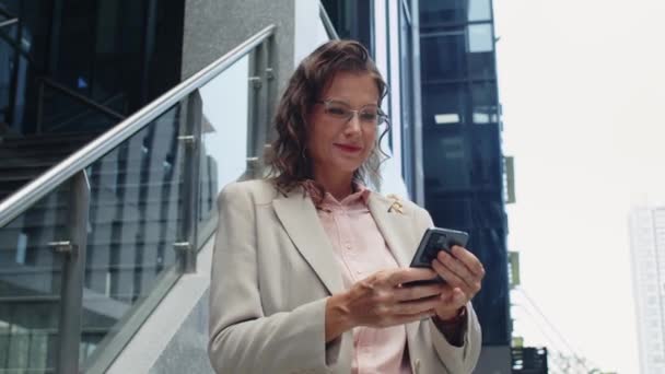 Низкоугловой Портрет Веселой Деловой Женщины Средних Лет Проверяющей Сообщения Смартфоне — стоковое видео