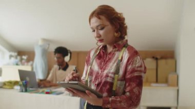 İş arkadaşıyla dikiş atölyesinde çalışırken tablet bilgisayardaki Asyalı terzi doldurma formunun portresi