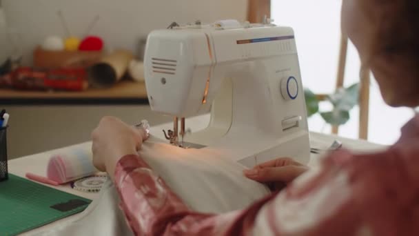 在工作室的缝纫机上用织物缝制的无法辨认的裁缝店的肩上 — 图库视频影像