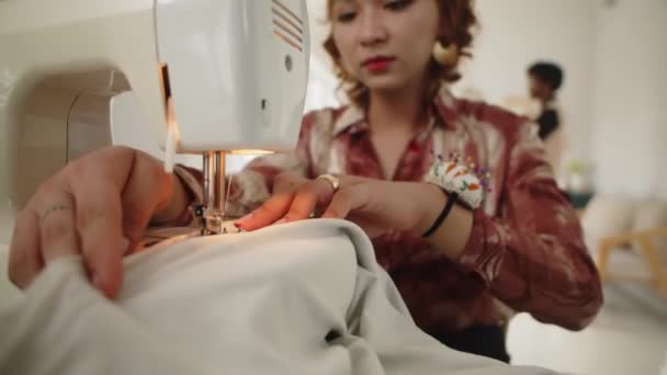 专注于亚洲女性裁缝使用缝纫机在工作室与面料一起工作的双手 — 图库视频影像