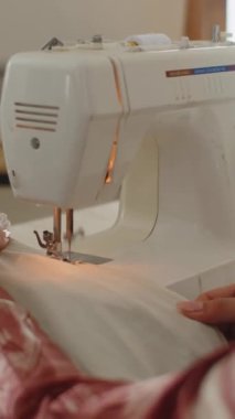 Atölyede dikiş makinesi üzerinde çalışan tanınmayan bir terzinin dikey çekimleri
