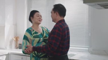 Yaşlı Asyalı çiftin evde romantik dans ederken konuştuğu orta boy bir fotoğraf.