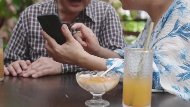 カフェで飲み物とデザートでテーブルに座ってスマートフォンで写真を撮る方法を学ぶ熟年配偶者のクロップショット — ストック動画