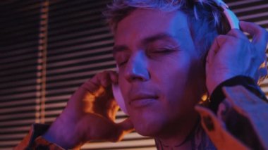 Boynunda dövmesi olan, kulaklıkla müzik dinlerken şarkı söyleyen beyaz bir adam.