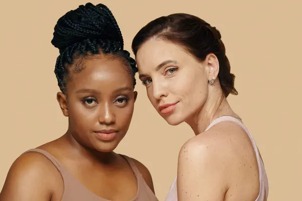 Portrait of diverse women standing against beige background