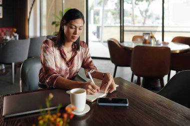 Bayan restoran sahibi planlarını ve fikirlerini planlayıcıya yazmış.