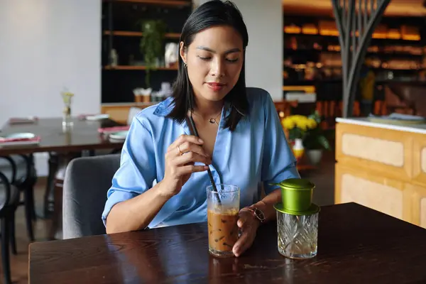 笑顔ベトナム女性がレストランでアイスコーヒーを飲む ロイヤリティフリーのストック写真