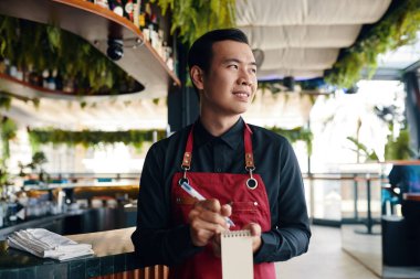 Gülümseyen Vietnam restoranı garsonu siparişi yazıyor.