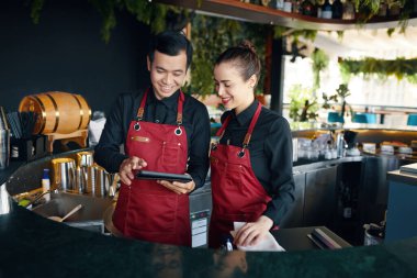 Gülümseyen barmenler tablet bilgisayardan siparişleri kontrol ediyorlar