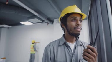Düşük açılı siyahi inşaat işçisi telsizle takımla iletişim kuruyor.