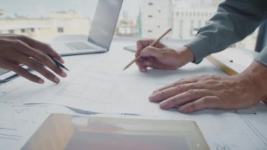 Tanımlanamayan mühendislerin ellerinin altında. Masanın planına oda ölçümleri yazıyorlar.