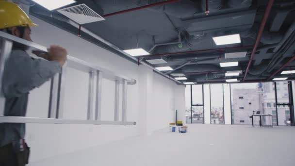 Отслеживающий Снимок Азиатского Строителя Несущего Лестницу Работающего Над Ремонтом Помещения — стоковое видео