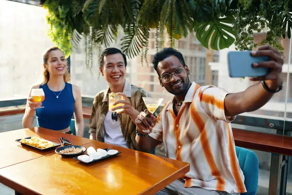 Homem Animado Tomando Selfie Com Amigos Quando Sentado Mesa Bar — Fotografia de Stock