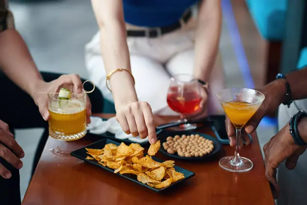 Hands of people having drinks and appetizers when spending evening in bar