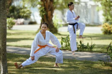 Tekvando sporcuları idmandan önce şehir parkında ısınıyorlar.