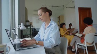 Ofiste çalışırken kablosuz bilgisayar kullanan beyaz kadın bilişim uzmanı.