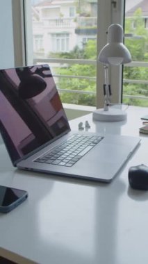 Bilgisayarı, akıllı telefonu ve lambası olan bir ofis masasının dikey görüntüsü.