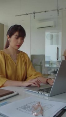 Modern ofiste bayan Asyalı yöneticinin kablosuz bilgisayarla çalışırken dikey çekimi.