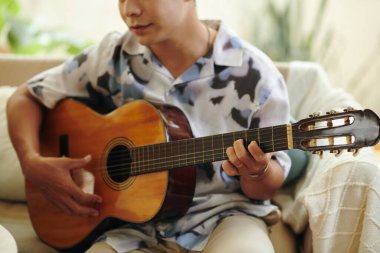 Evde gitar çalan yaratıcı adamın kırpılmış görüntüsü