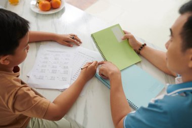 Baba oğluyla matematik ödevi yapıyor, yukarıdan bakıyor.