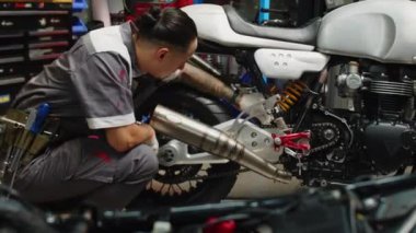 Çoklu etnik çeşitlilikte bir tamirci müşterilerin motosikletini tamir atölyesinde çalışırken kontrol ederken geniş açı