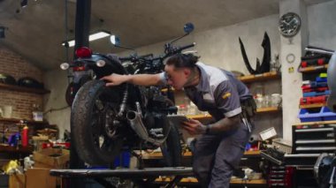 Garajdaki motorsikletin neden bozulduğunu inceleyen tablet bilgisayarlı çok ırklı bir uzman olma ihtimali çok düşük.