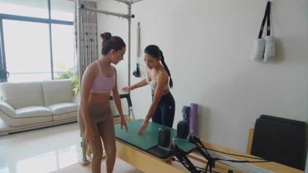 长期训练的女教练教年轻的亚洲女子如何使用健身器材 — 图库视频影像