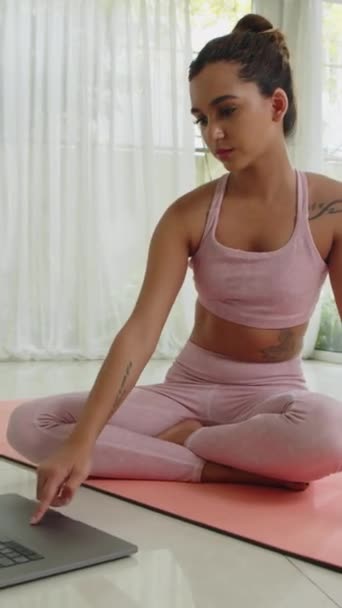 年轻女运动员在家里做瑜伽垫在线训练时使用笔记本电脑的纵向照片 — 图库视频影像