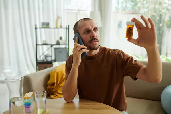 Hombre Ansioso Llamando Médico Para Preguntar Qué Pastillas Tomar Imagen de archivo