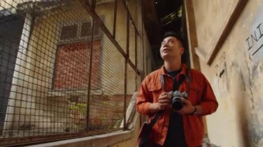 Asyalı erkek fotoğrafçının terk edilmiş yerlerin fotoğraflarını çekerken çekilmiş bir fotoğrafı.