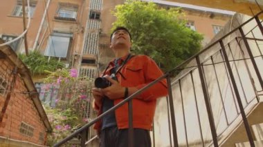 Heyecanlı Asyalı blogcu şehir manzaralarını çekerken alçak açı