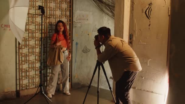 古風な建物の内側に装飾された壁にポーズする若い女性モデルの写真を撮る男性写真家のロングショット — ストック動画