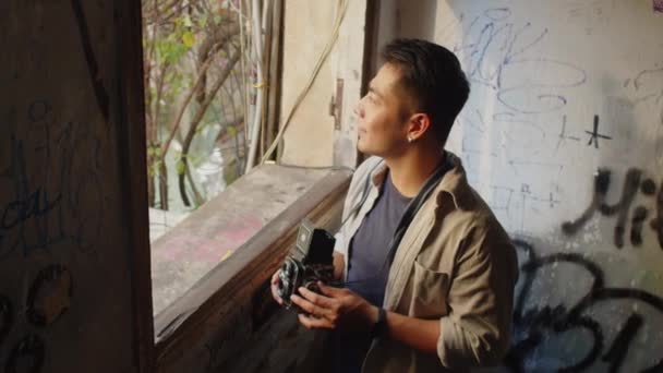 Asyalı Bir Adamın Eski Binanın Penceresinden Eski Bir Kamerayı Çekerken — Stok video