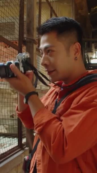 Asyalı Erkek Fotoğrafçının Dikey Portresi Terk Edilmiş Yerleşim Alanının Fotoğraflarını — Stok video